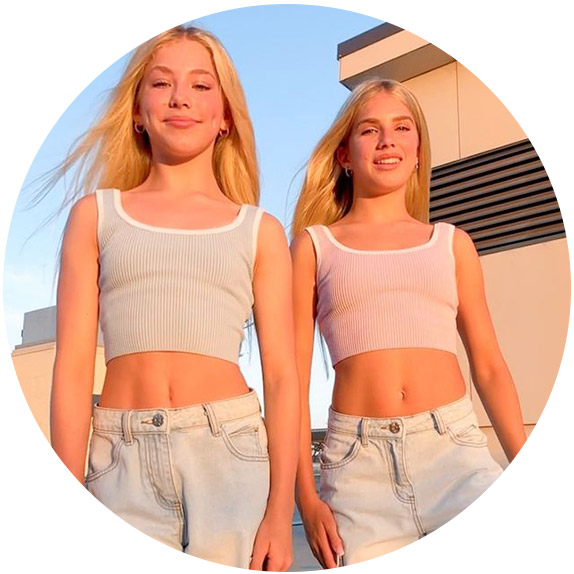 Two blonde girls wearing matching tops and jeans