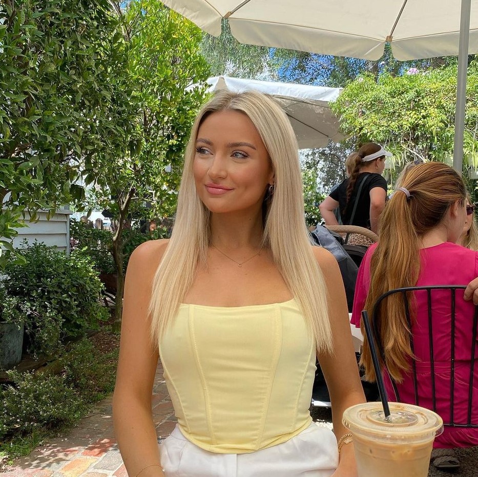 Blonde woman sitting at a table wearing a lemon coloured top