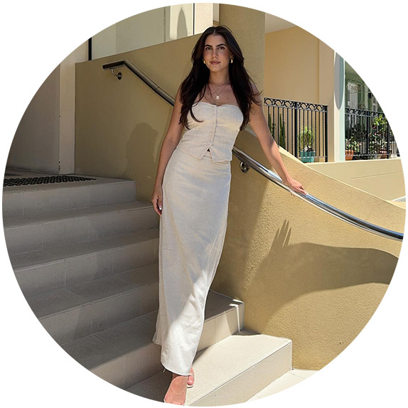 woman in a white top and matching skirt standing on stairs